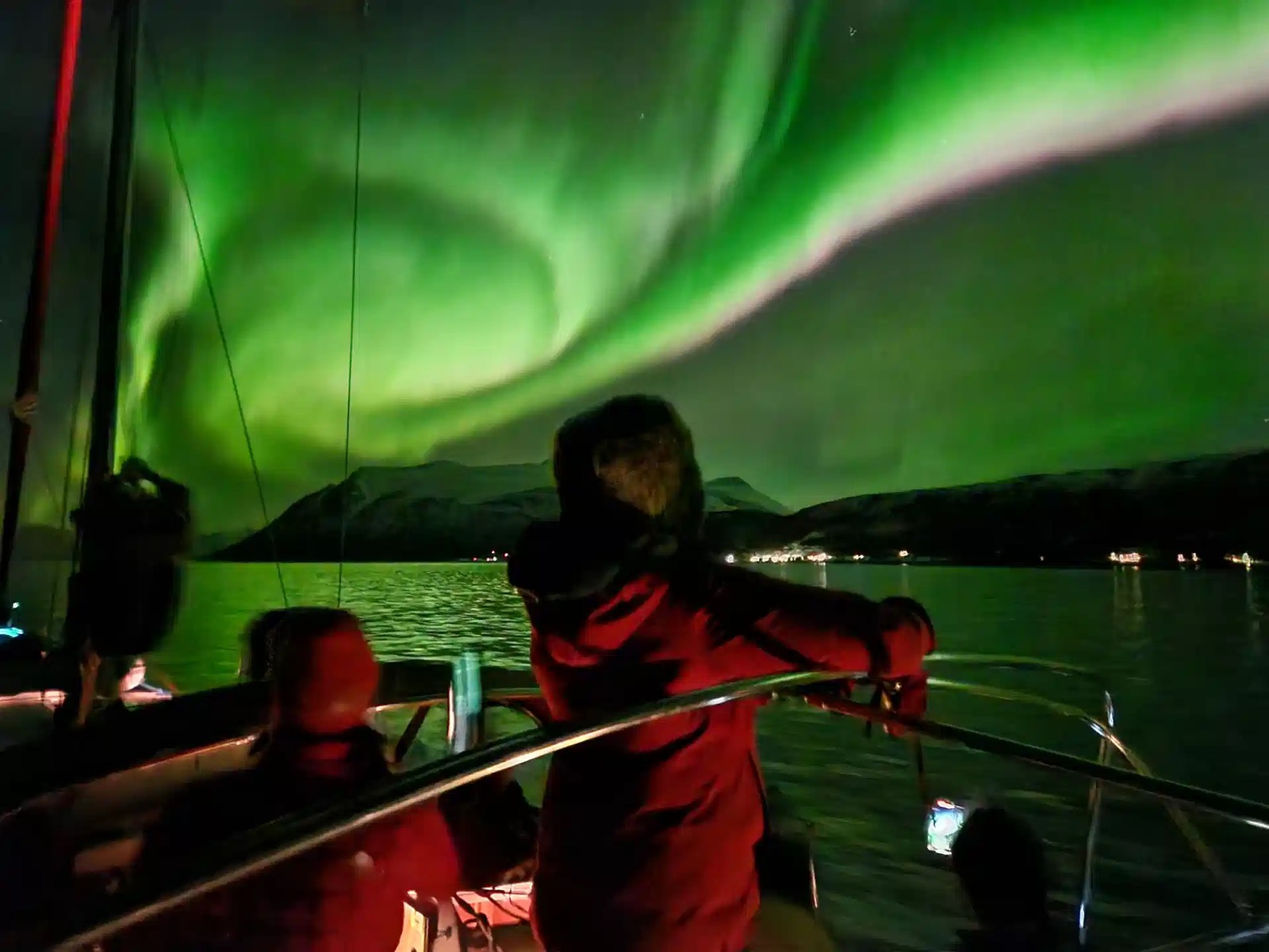 Guests on deck watching the northern lights over a fjord near Tromsø